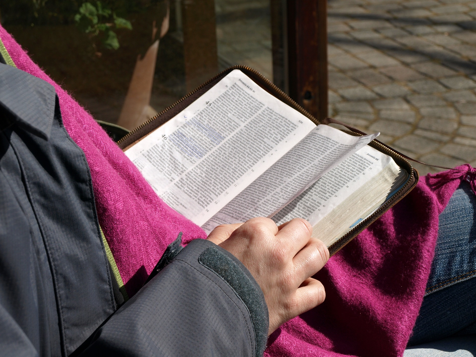Photo of a person reading a Bible outside.